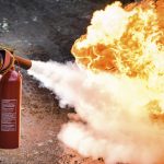 A man using a carbon dioxide fire extinguisher to fight a fire.